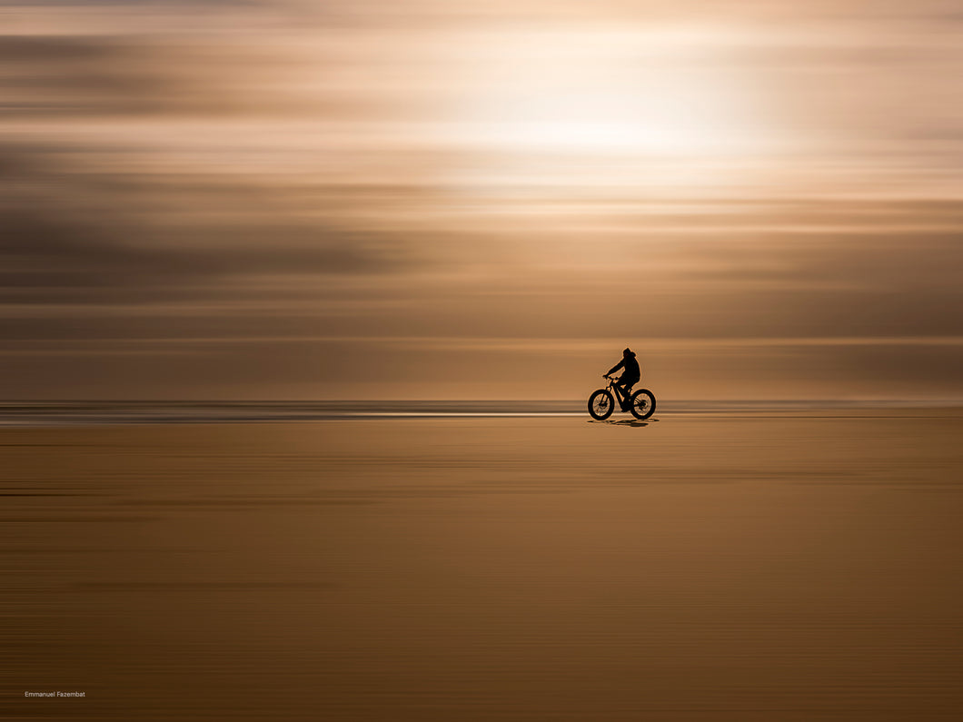 Photographie minimaliste d'un cycliste sur son Vélo, ridant sur la plage de l'océan au soleil couchant, pointe du Cap Ferret, effet de filage.